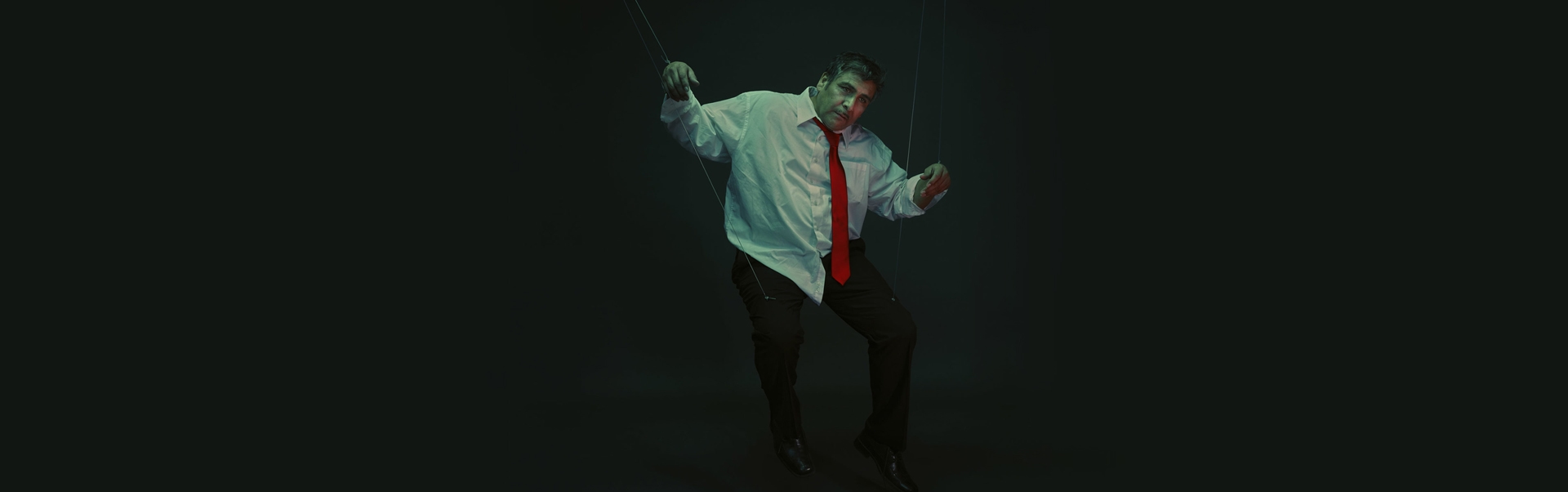 A Hispanic/Latino man as a puppeteer in a dark room