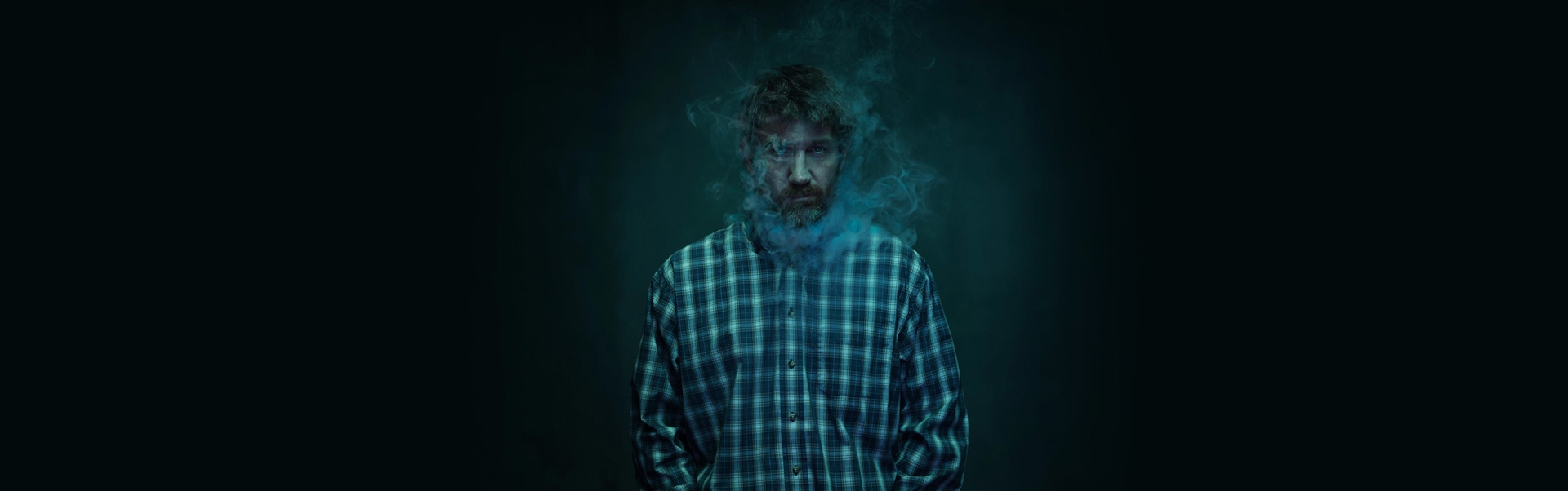 Man in dark background with smoke around his face