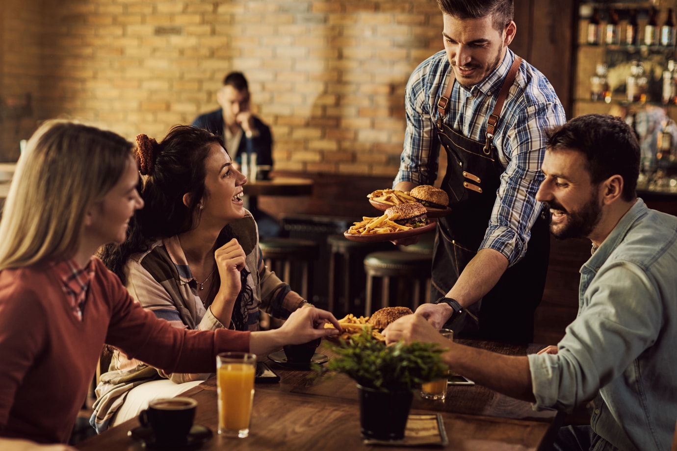 Friends at dinner, being served burgers and fries