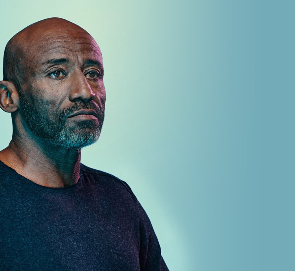 An African American/Black man with a light colored background behind him