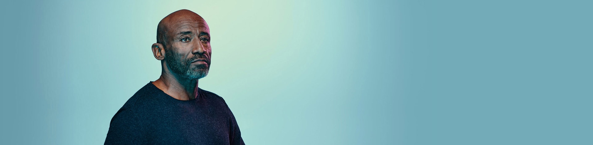 An African American/Black man with a light colored background behind him