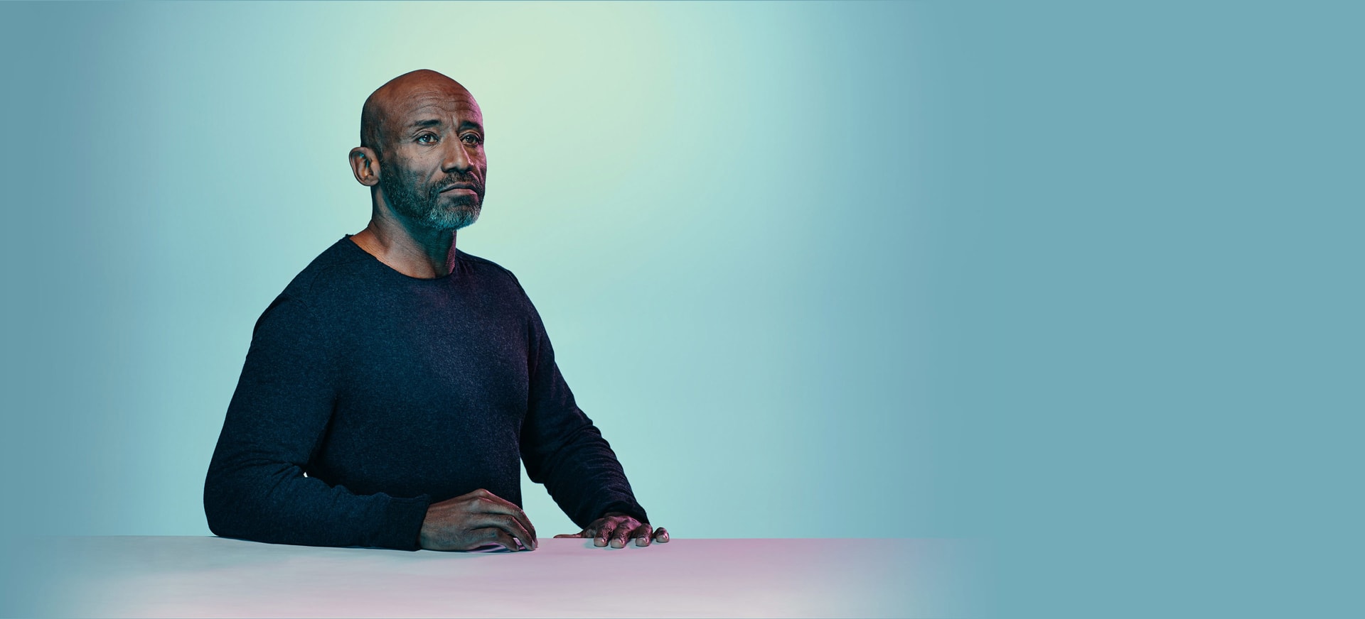 An African American/Black man sitting down in a light background