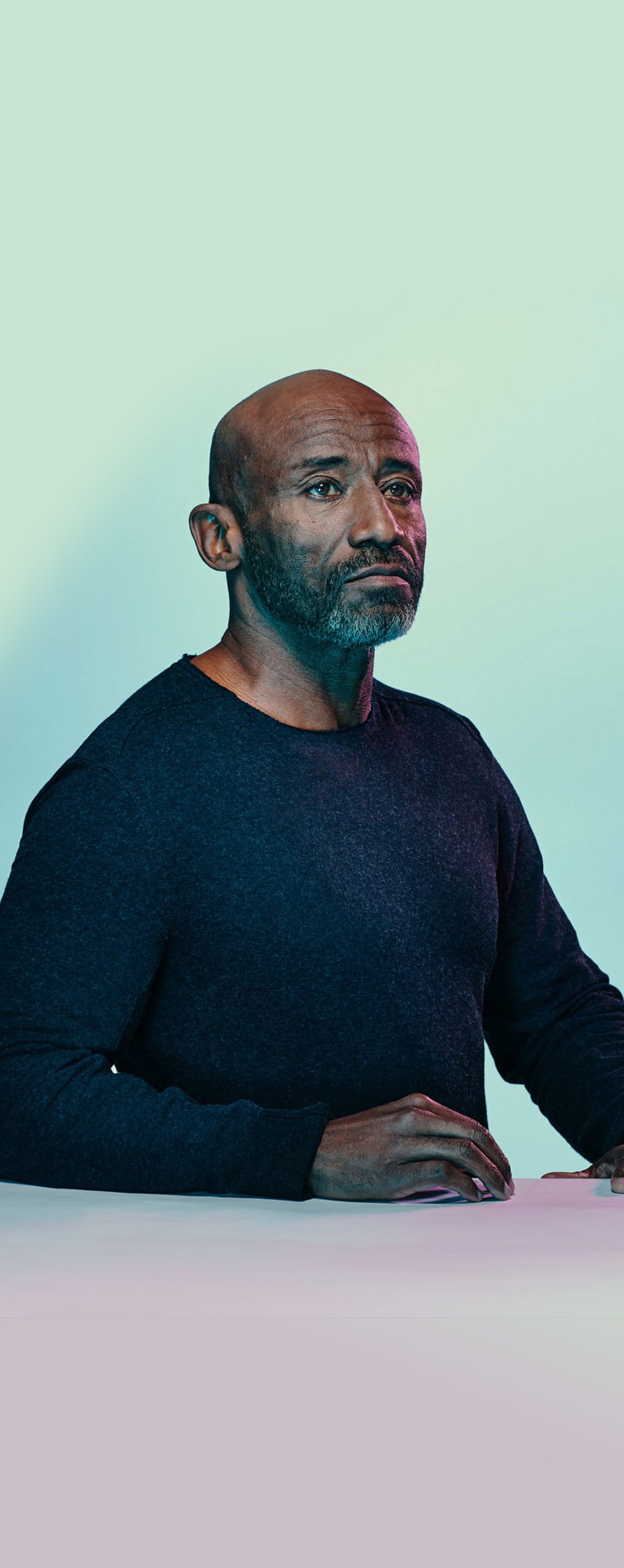 An African American/Black man sitting down in a light background