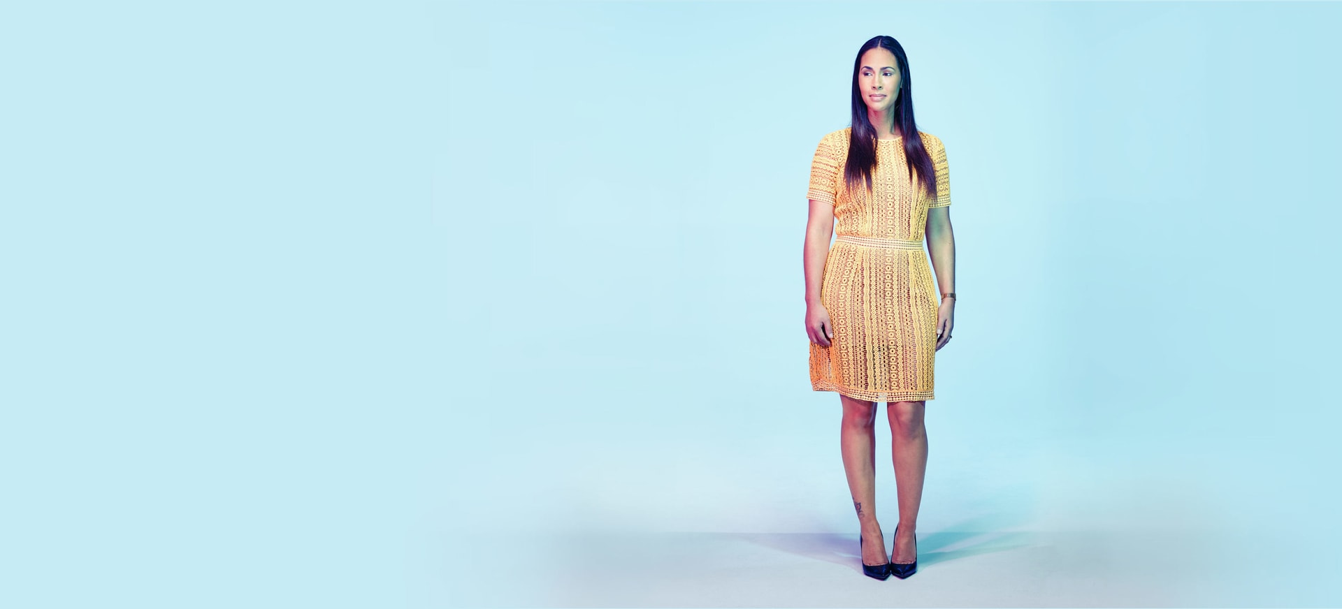 An American Indian woman in a yellow dress standing in a bright room