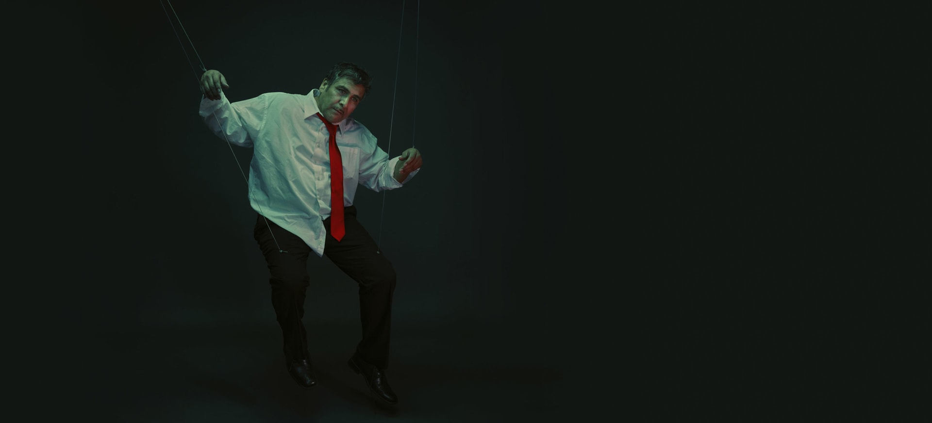 A Hispanic/Latino man in a dark room made into a puppeteer