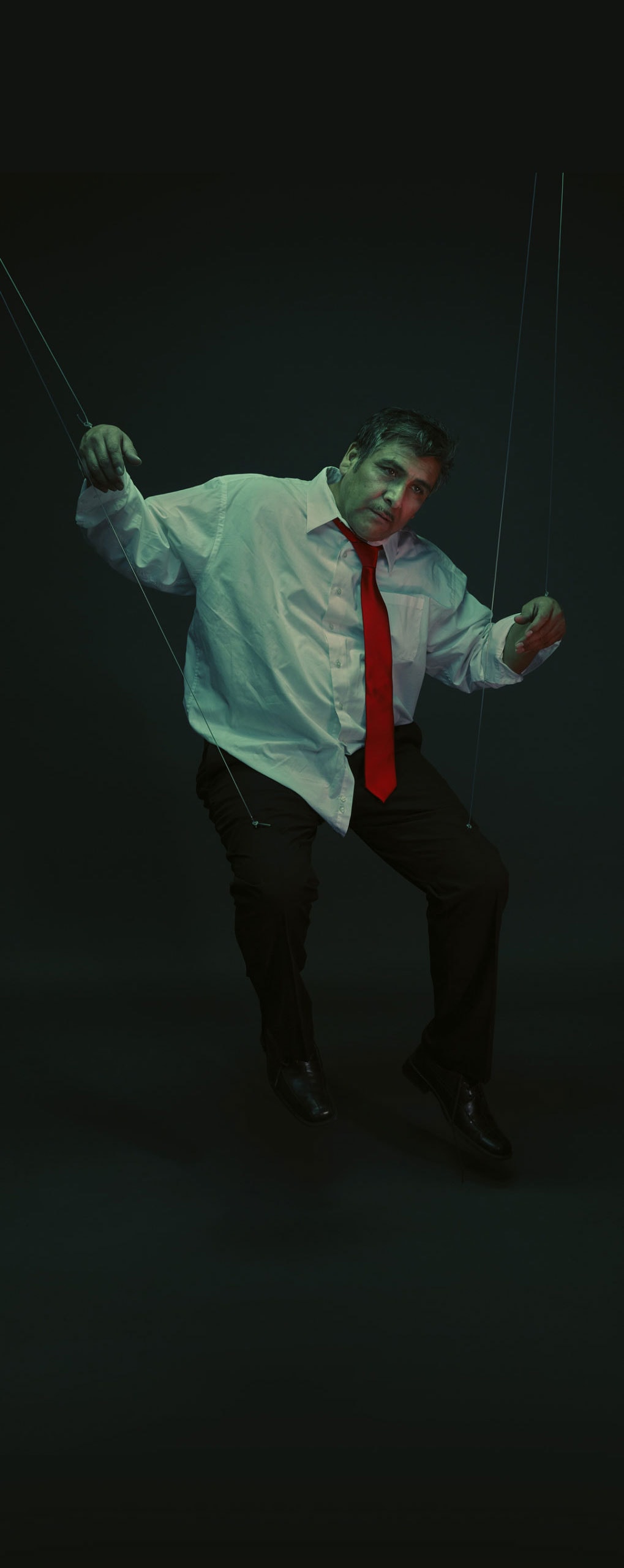 A Hispanic/Latino man in a dark room made into a puppeteer