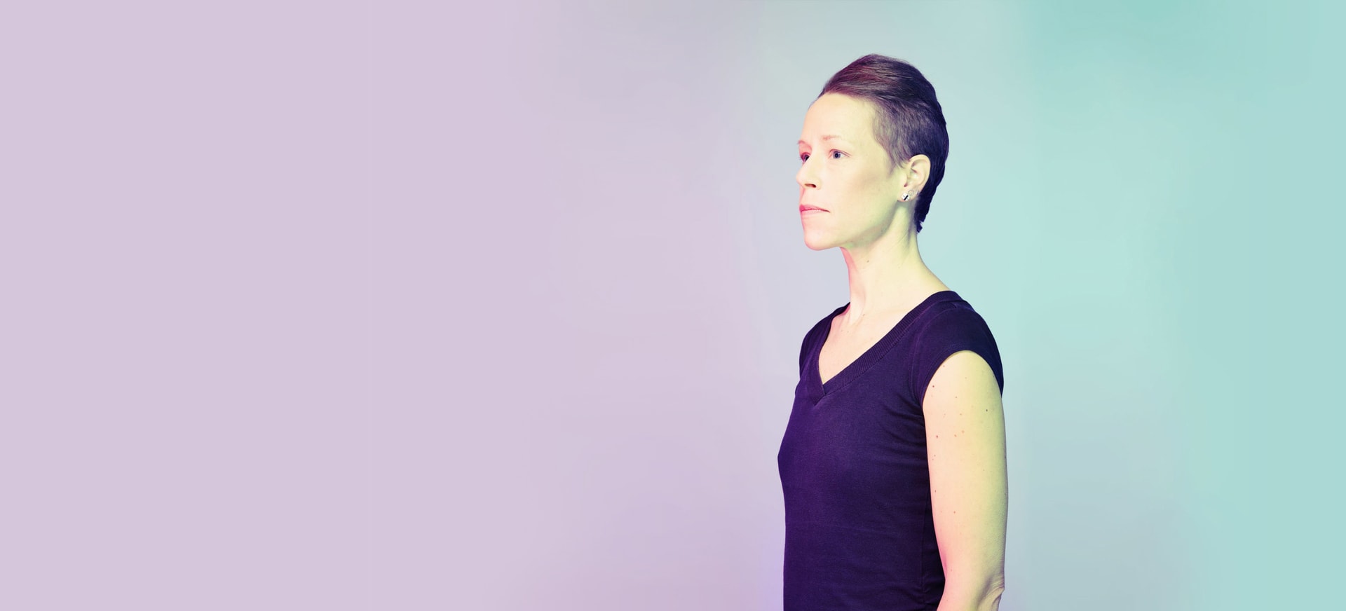 A non-binary person looking away in a light background