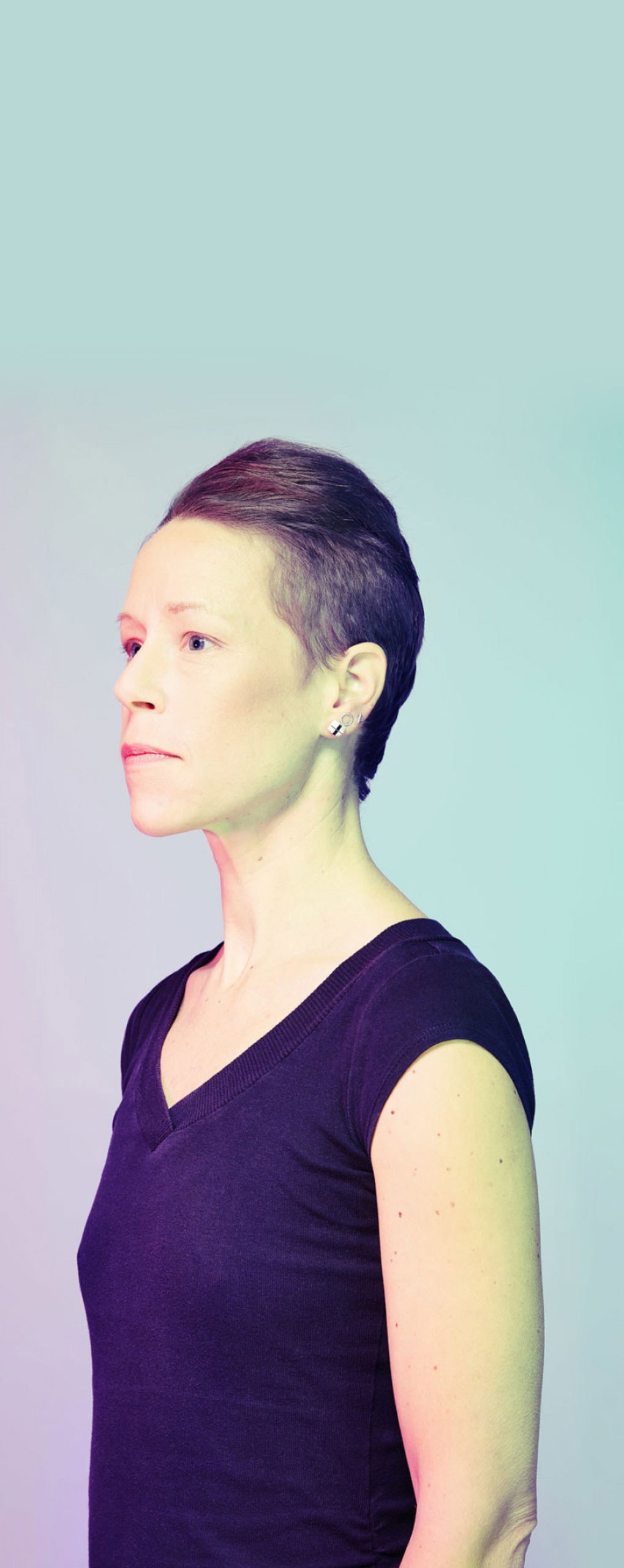 A non-binary person looking away in a light background