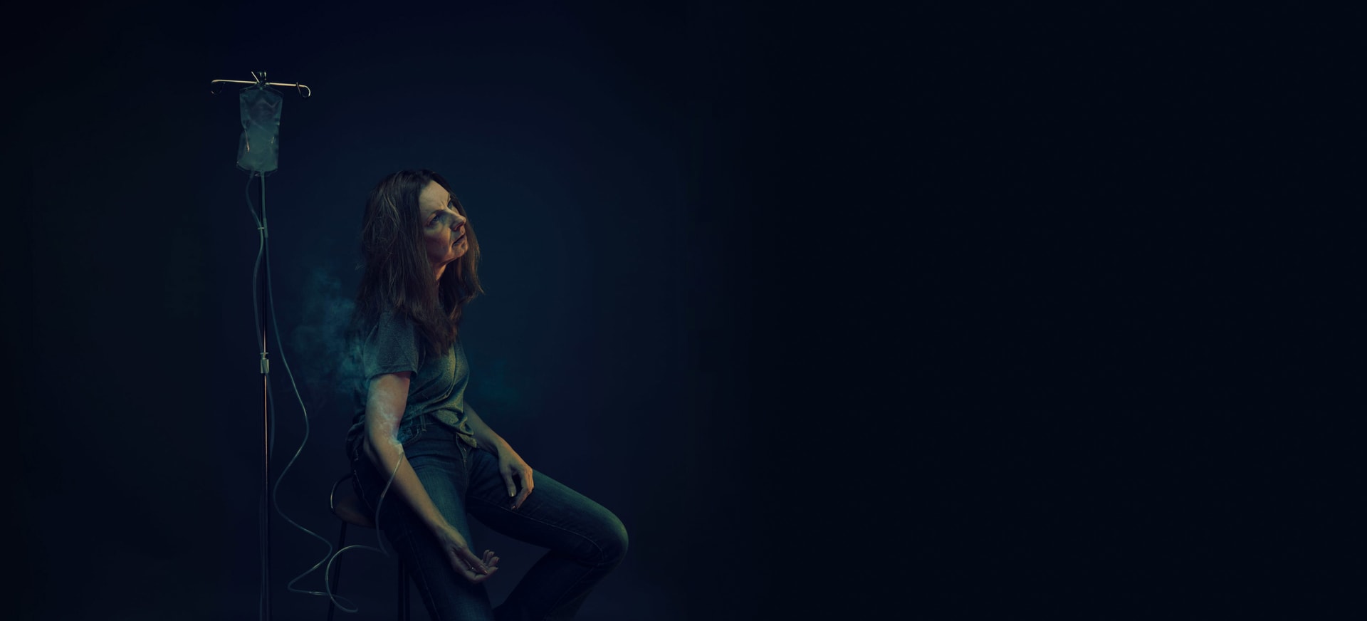 Woman sitting in the dark with IV bag filled with smoke