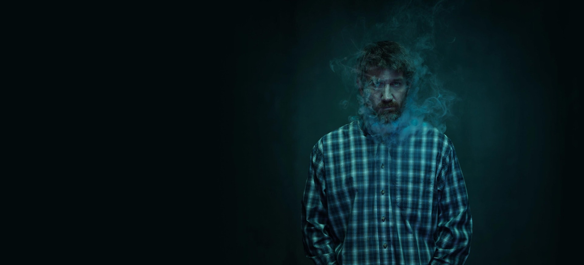 Man in dark background with smoke around face
