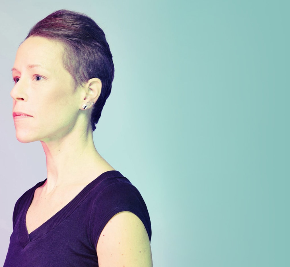A non-binary person looking away in a light background