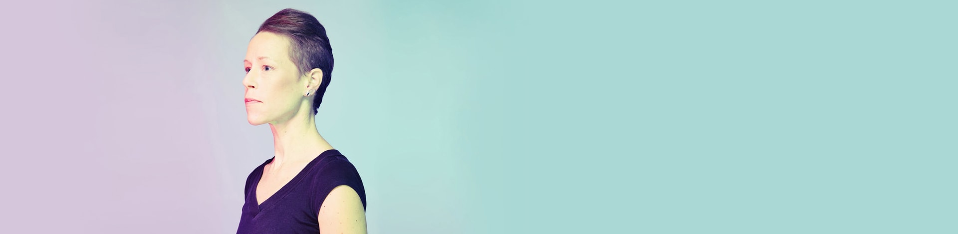A non-binary person looking away in a light background