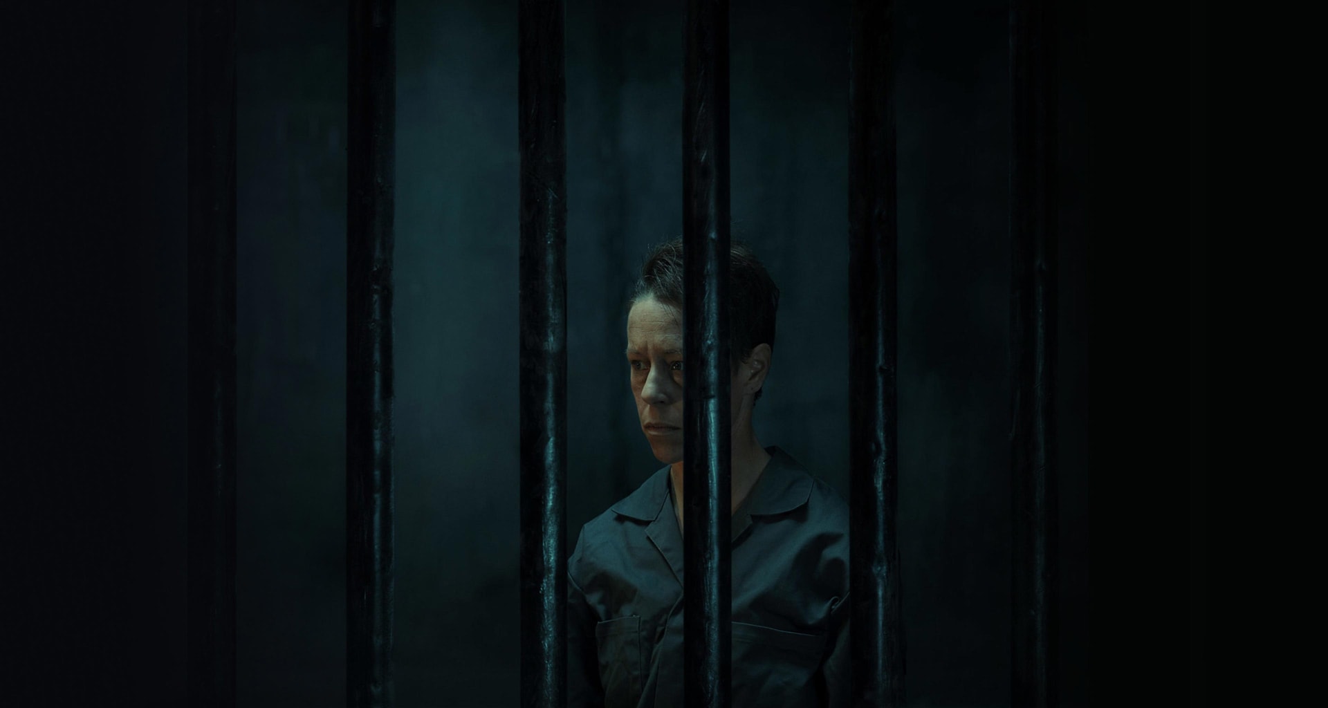 A non-binary person in a dark jail cell