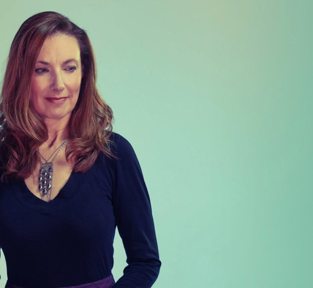 A woman slightly smiling in a light background