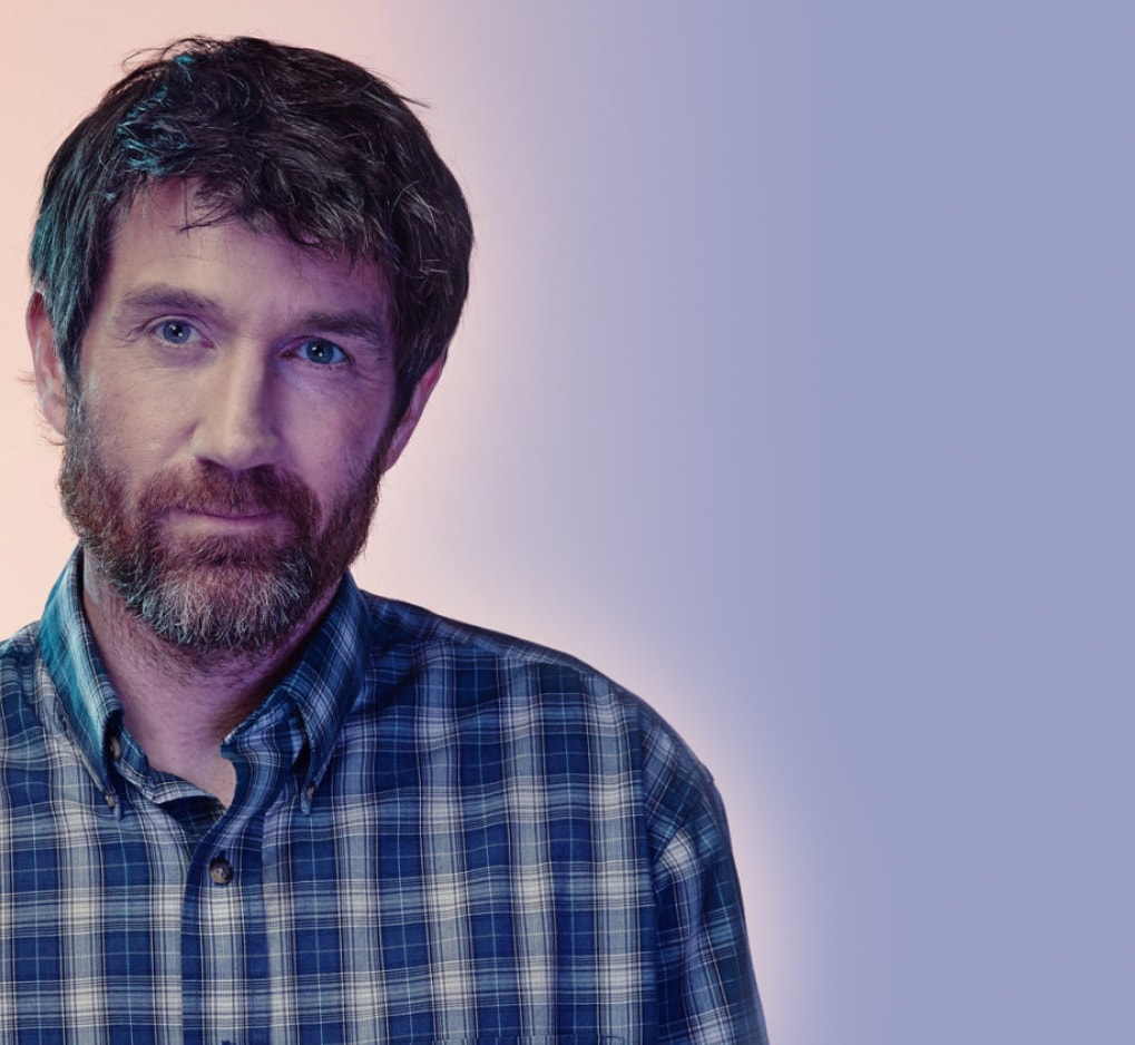 A man in a plaid shirt and light background