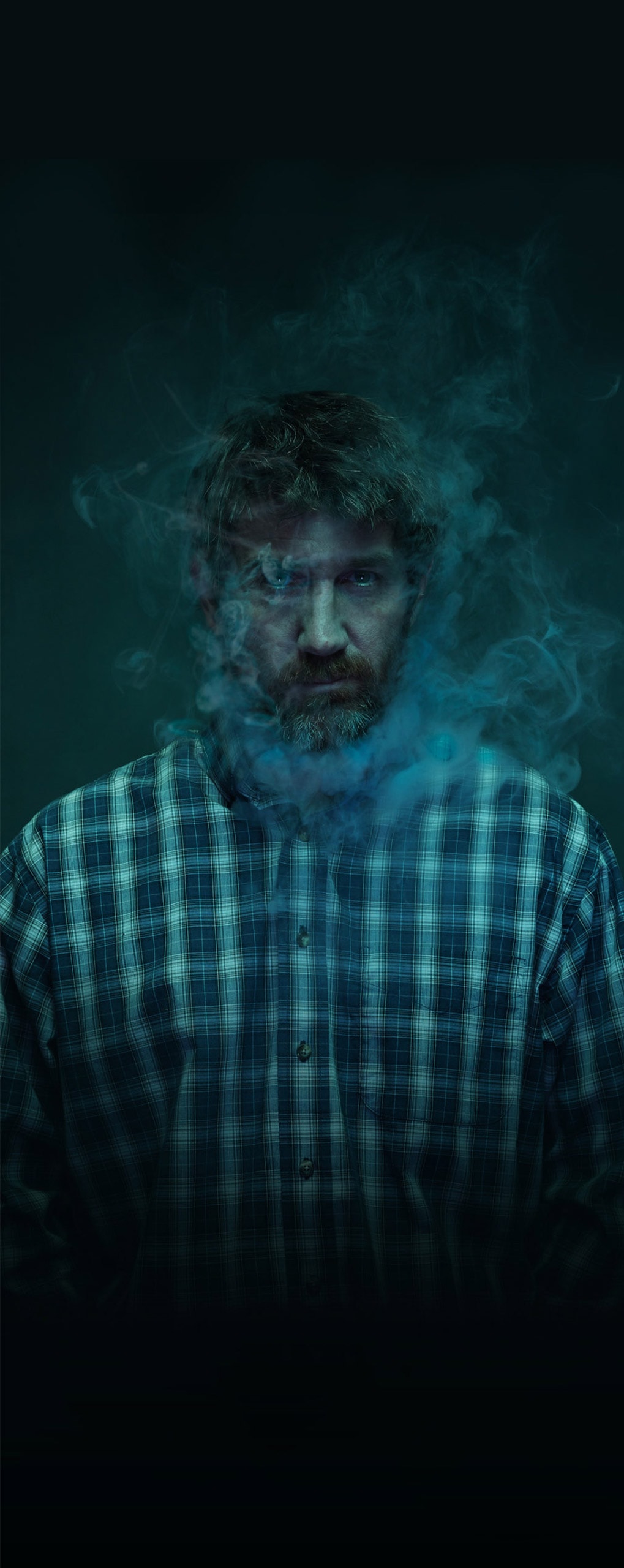 Man in dark background with smoke around face