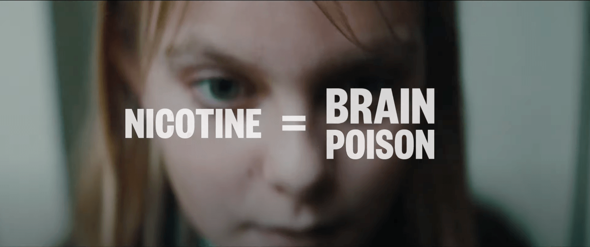 closeup of a girl's anxious face with the slogan Nicotine = Brain Poison superimposed on top