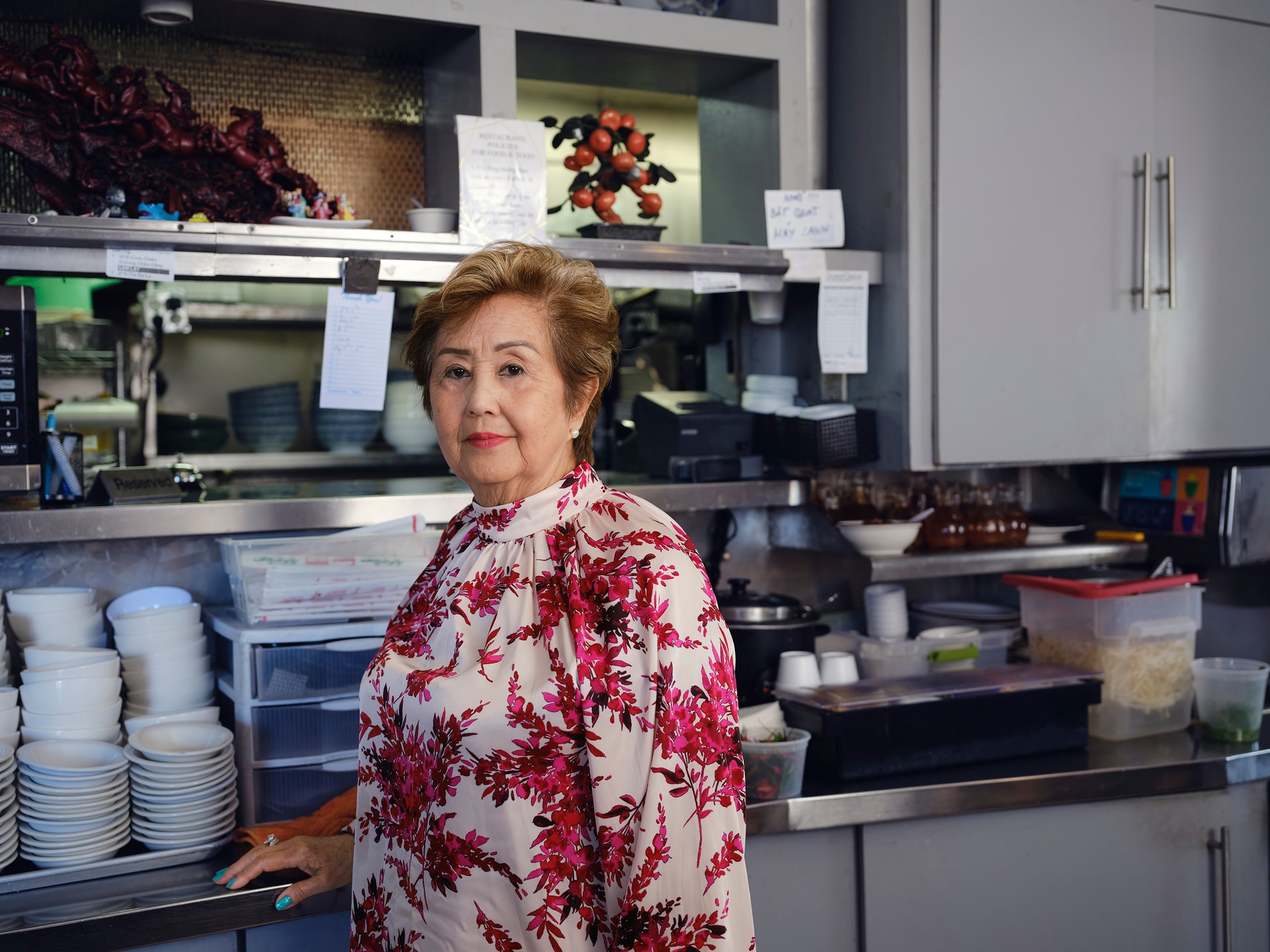 Tran My, an older businesswoman, stands in her restaurant
