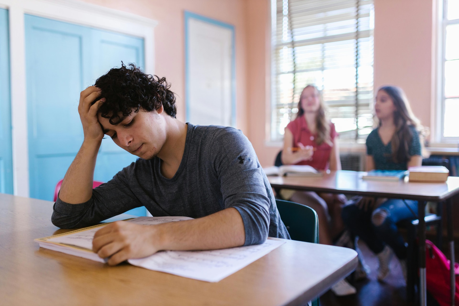 Teenage boy in the classroom at his desk looking distressed.