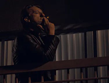 hombre fumando en un balcón
