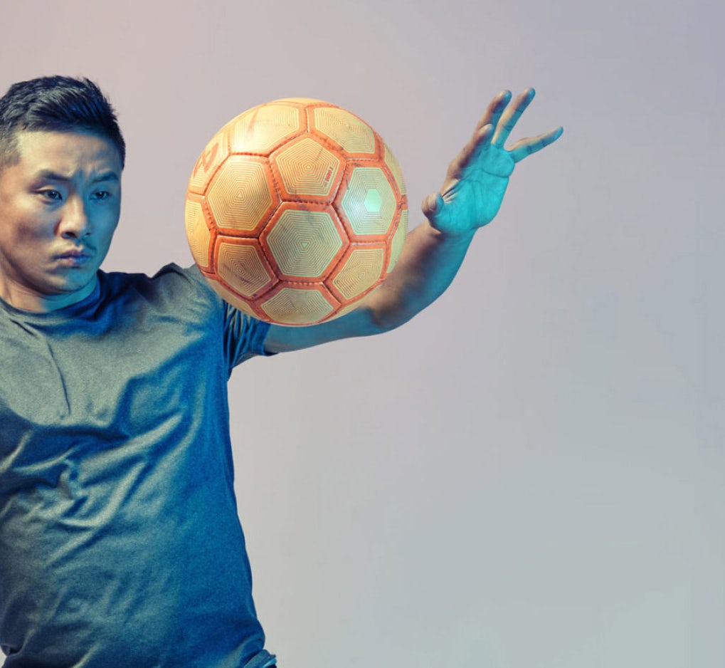 An Asian/Pacific Islander man with a soccer ball