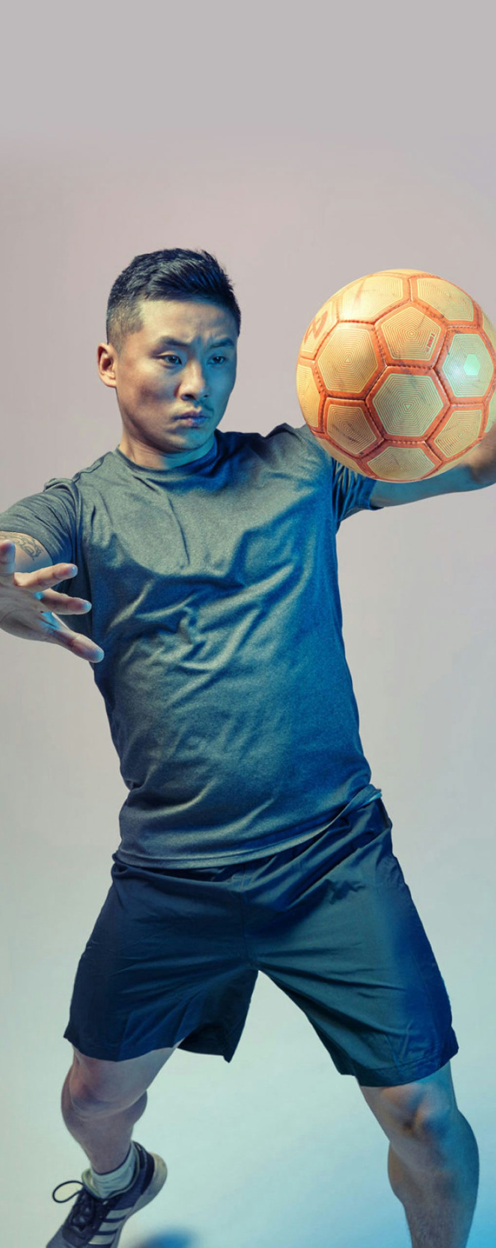 An Asian/Pacific Islander man playing with soccer ball