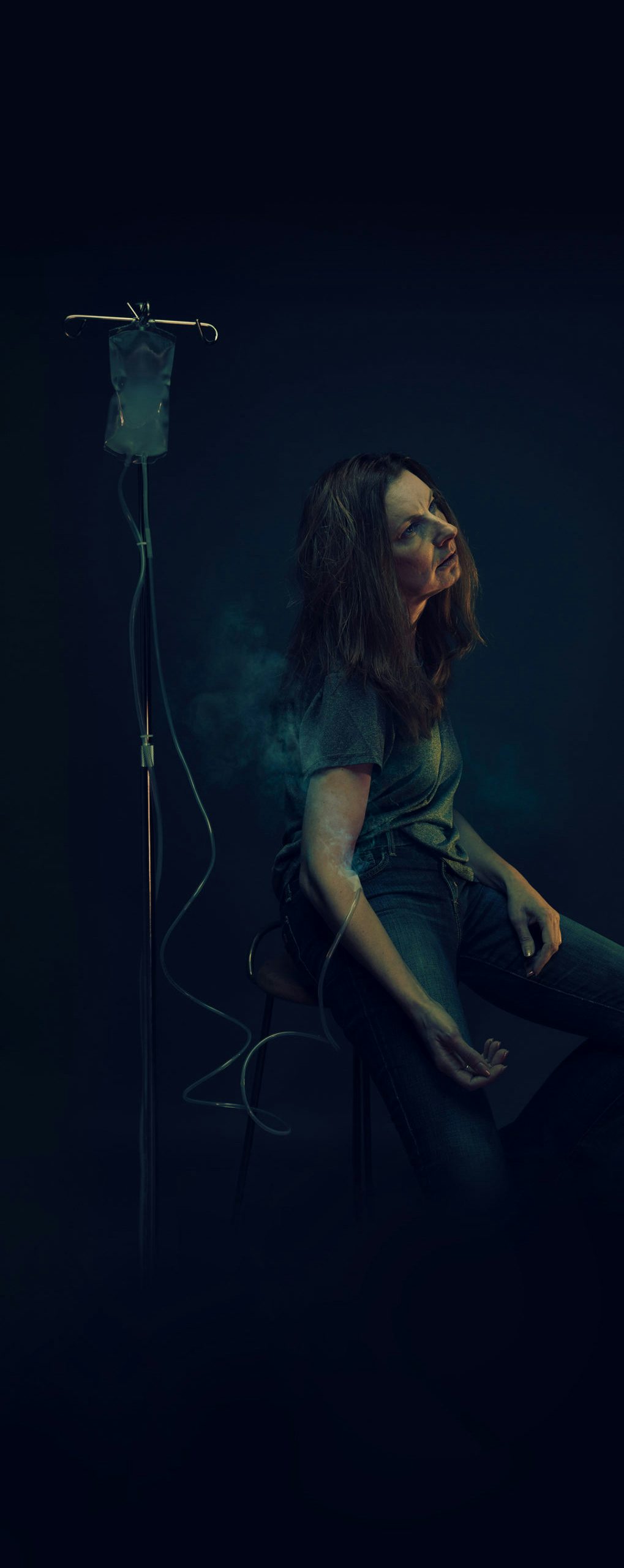 Woman sitting in the dark with IV bag filled with smoke