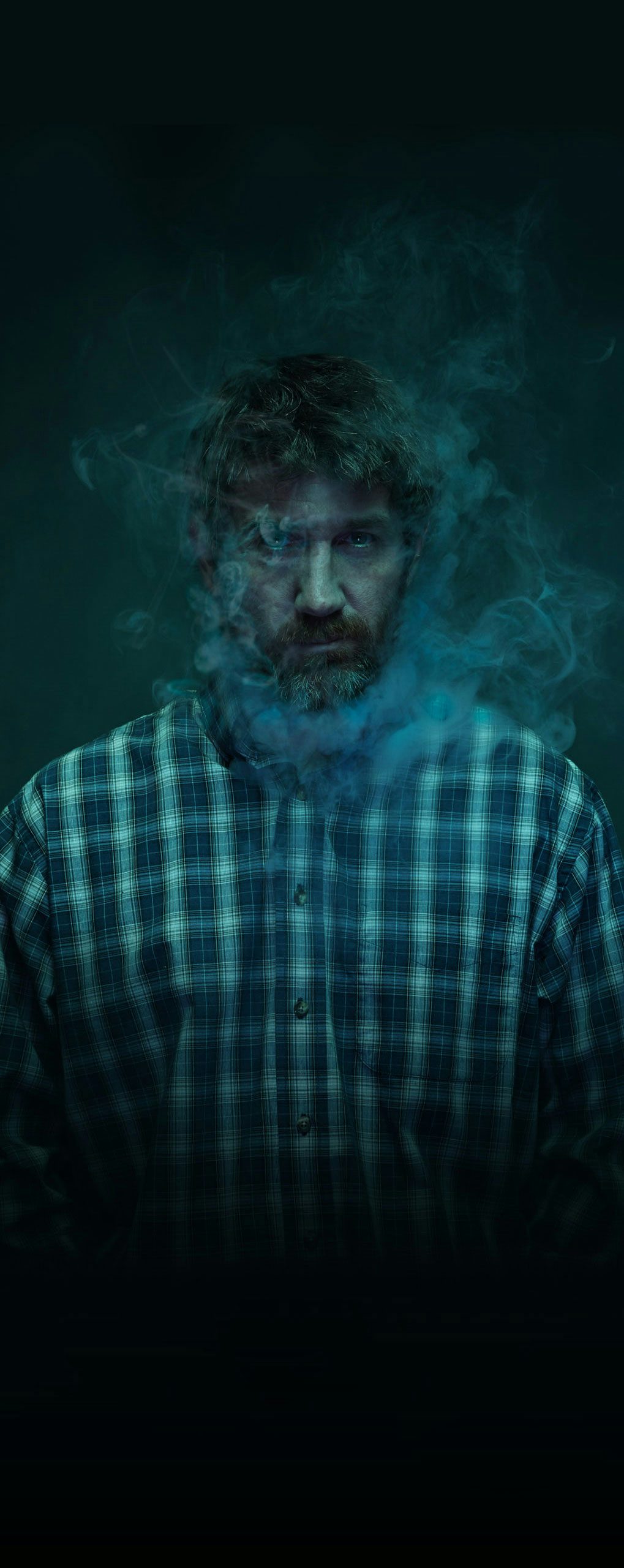 Man in dark background with smoke around face