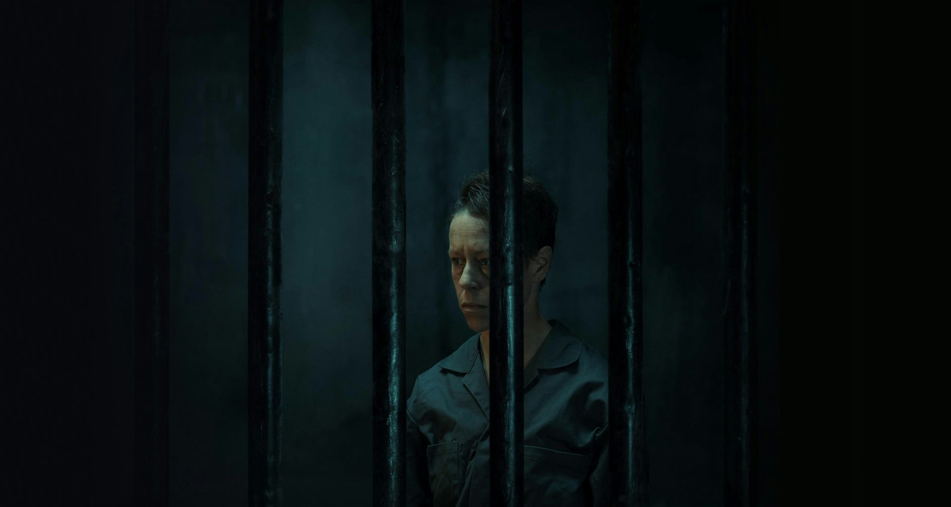 A non-binary person in a dark jail cell